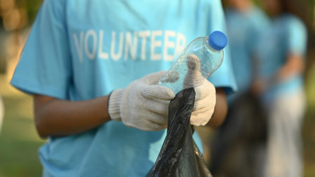 Cropped shot of female volunteer collecting garbage in public park. Charity and ecology conceptの写真素材