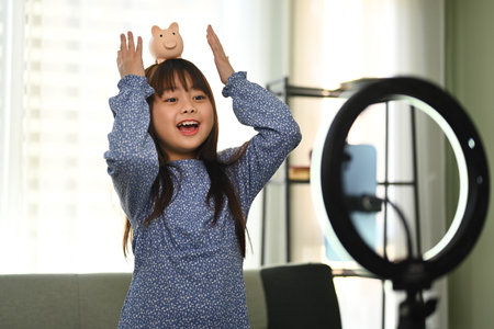 Cheerful kid blogger recording video blog about toys on smartphone to social networks.