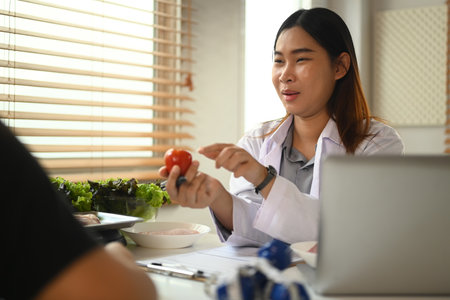 Asian female nutritionist giving consultation to patient in weight loss clinic. Nutrition and diet concept.の写真素材