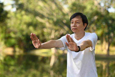 Concentrated Asian senior man doing Qigong exercises in the park. Healthy lifestyle concept.の写真素材