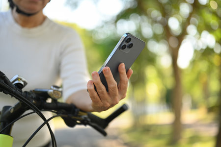 Select focus on senior woman hand using mobile phone while resting after riding exercise bicycleの写真素材