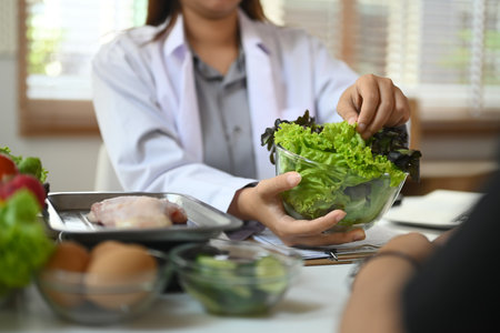 Professional nutritionist in white coat consulting client at table with organic vegetables and fruits.の写真素材