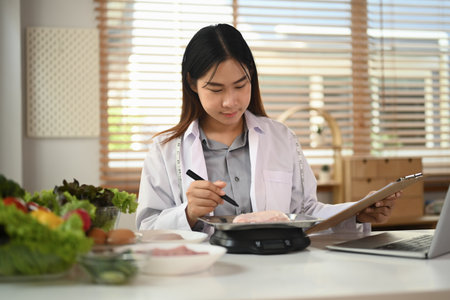 Smiling female nutritionist working at table with fresh vegetables and healthy productsの写真素材