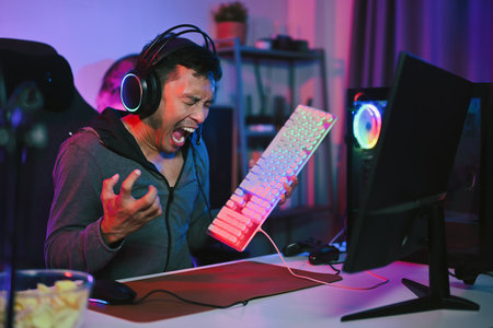 Angry gamer screaming and breaks keyboard, upset because of losing the gameの写真素材