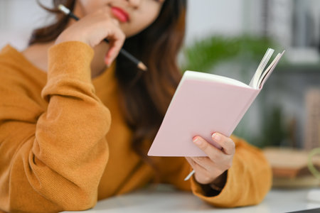 Young woman reading journal or checking working schedule plan at deskの写真素材