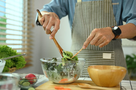 Middle age man mixing various vegetable in salad bowl. Healthy lifestyle and dieting conceptの写真素材