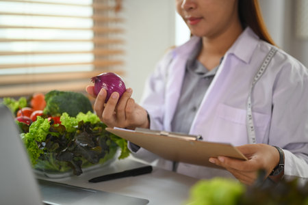 Nutritionist in white coat working on a diet plan at desk fresh vegetable and fruit. Health care conceptの写真素材