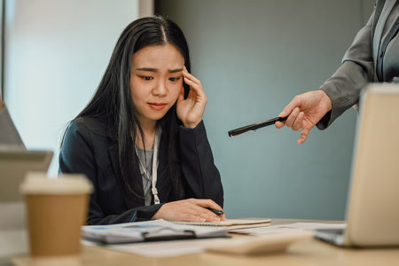 Upset asian female employee being scolded by supervisor complaining about workの写真素材