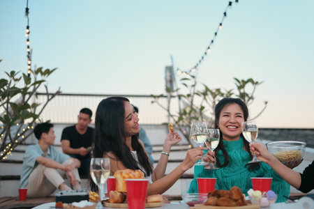 Happy young people having fun on rooftop party clinking with drinks.の写真素材