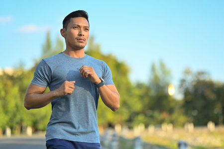 Handsome muscular sporty man jogging in the park on a sunny day. Healthy lifestyle conceptの写真素材