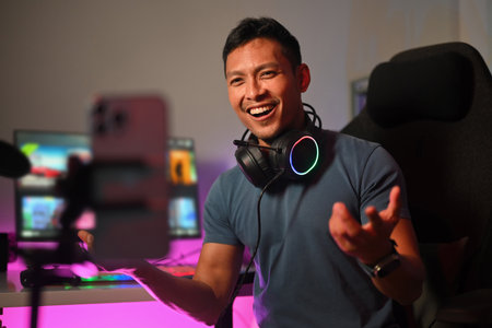 Attractive male gamer talking to audience during live streaming at gaming room.の写真素材