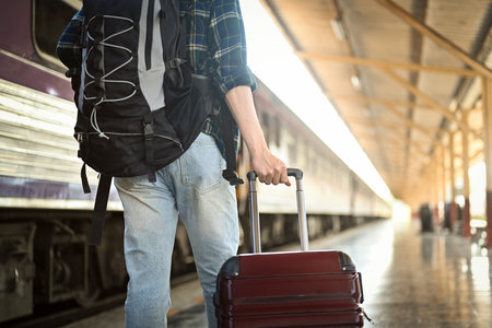 Male tourist walking with a luggage walking at the railway station, ready for a journey.の写真素材