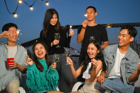 Group of young adult friends laughing and having fun at rooftop party. Friendship lifestyle concept.の写真素材