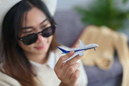 Happy young woman traveler in sunglasses holding airplane model. Traveling, vacation and...