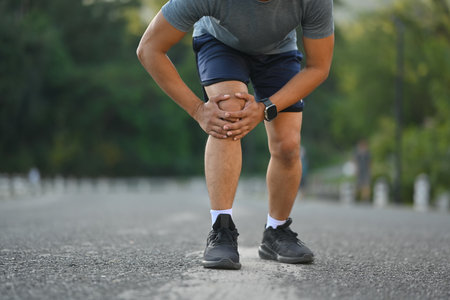 Male athlete suffering ligament injury during running workout, training. Sport and health care...