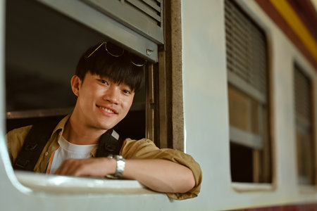 Happy male passenger leaning out off a train window while traveling. Transportation, people and traveling conceptの写真素材