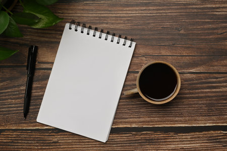 Flat lay, Top view blank notepad, pen and cup of coffee on wooden table.の写真素材