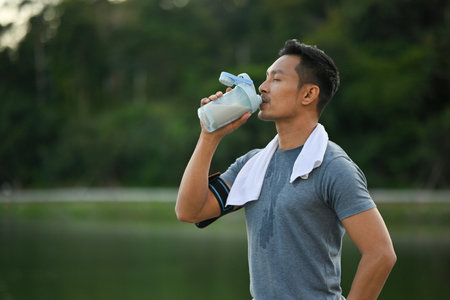 Portrait of sportsman drinking a protein and resting after jogging session in the morning.の写真素材