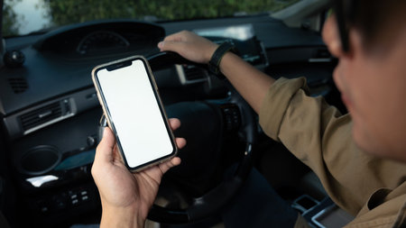 Cropped shot of man sitting behind wheel of car and using smartphone. Transportation and technology...