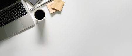 Top view laptop, coffee cup and notepad on white table with copy space.