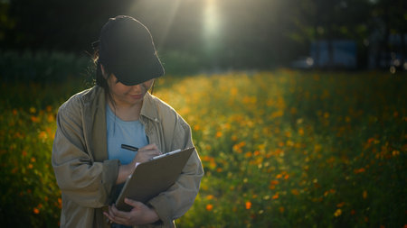 Young female agronomist writing notes working on an organic farm. Agriculture and cultivation...