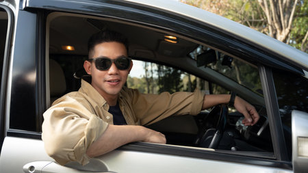 Attractive young man wearing sunglasses traveling by car in countryside.