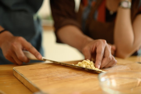 Man chopping garlic on wooden board, young couple preparing meal in the kitchen.の写真素材