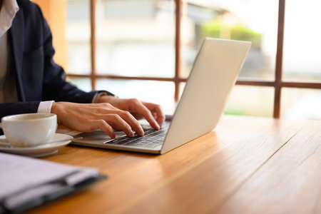 Cropped shot young businessman hands typing on laptop, working remotely at coffee shop.の写真素材