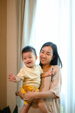 Happy young mother with her cute baby boy relaxing enjoy tender family moment at home.