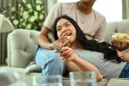 Romantic young couple relaxing at home watching tv and eating popcorn.