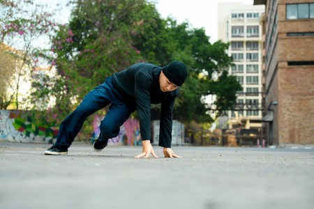 Young handsome male dancer in stylish clothes showing hip hop performance on the street.