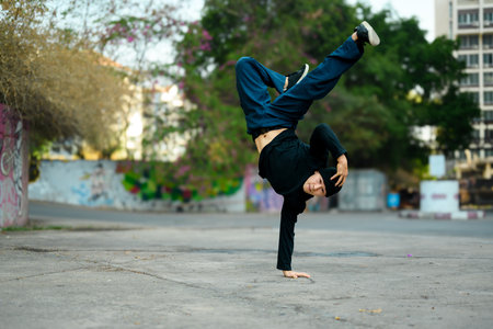Talented male hip hop dancer doing a handstand in urban area.