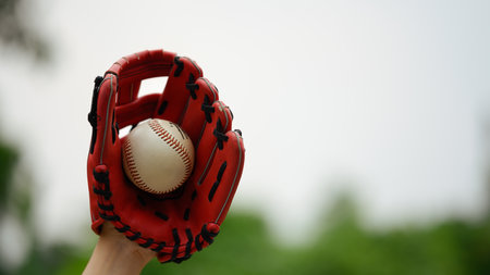 Hand in baseball glove catching a ball in the air. Sport, activity and people concept.