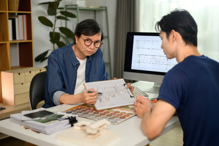 Interior designer man discussing building plan design project with his client at office.