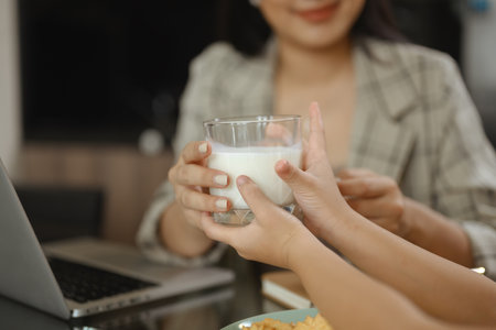 Beautiful Asian mother working at home and taking care of cute little daughter.の写真素材