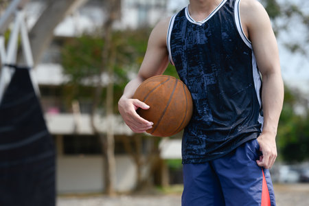 Basketball player holding a ball standing on a court. Sport, energy and healthy lifestyle concept.の写真素材