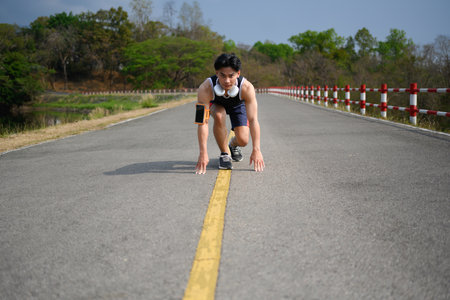 Motivated sportsman getting ready to start running in the park on sunny day.