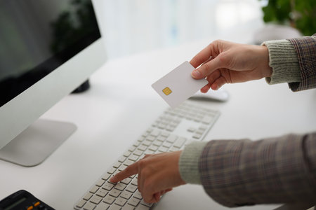 Woman holding plastic credit card and typing on computer keyboard. Online shopping concept.