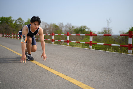 Full body length shot of sporty man in running start pose. Motivation and healthy lifestyle concept.