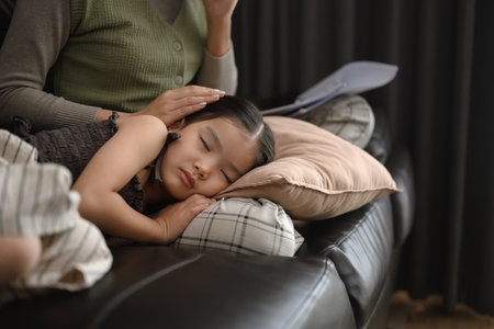 Cute little girl sleeping peacefully on sofa in her working mother.の写真素材