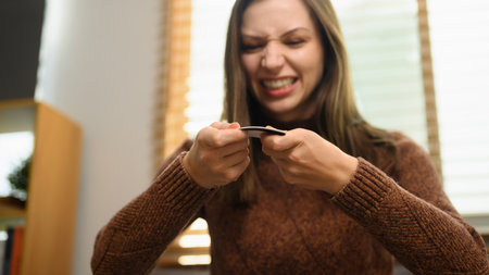 Upset young woman breaking her credit card. Financial problems concept.の写真素材
