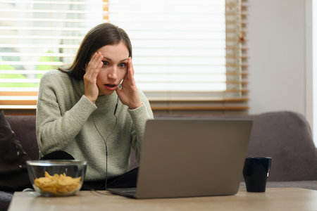 Carefree young caucasian woman watching movie on a laptop at home.