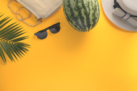 Straw hat, sunglasses, watermelon and palm leaf on yellow background. Summer and travel vacation concept.の写真素材