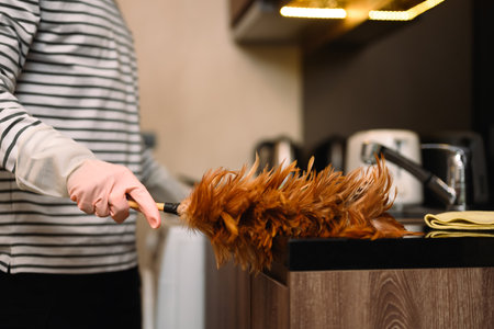 Closeup shot of man dusting kitchen with a feather duster. Housekeeping concept.の写真素材