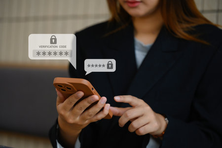 Young businesswoman typing on smartphone entering verification code for login. Cyber security concept.の写真素材