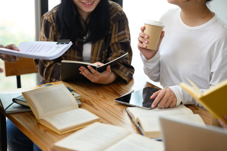 Group of college students working together for their project at table with books and laptop.の写真素材