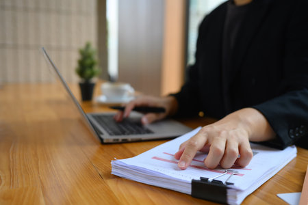Businessman analyzing marketing data and using laptop on wooden table in office.の写真素材