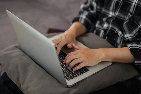 Cropped shot of male freelancer working with laptop on couch at home.