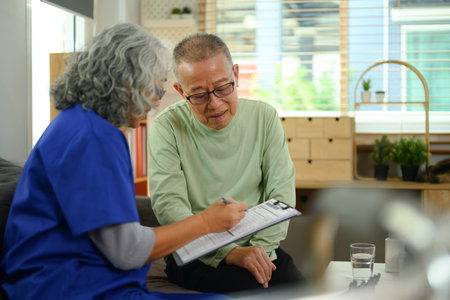 Friendly doctor sharing good news about health test results to elderly patient being in home visit.の写真素材