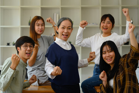 Group of happy university students and mature professor celebrating success in the classroom.の写真素材